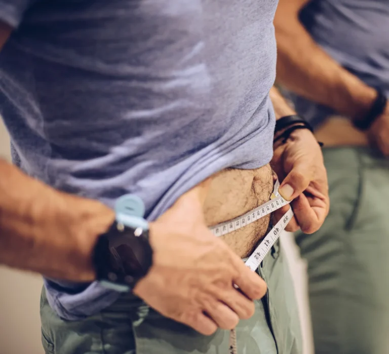 A woman using a measuring tape around her waist, symbolizing successful medical weight loss.